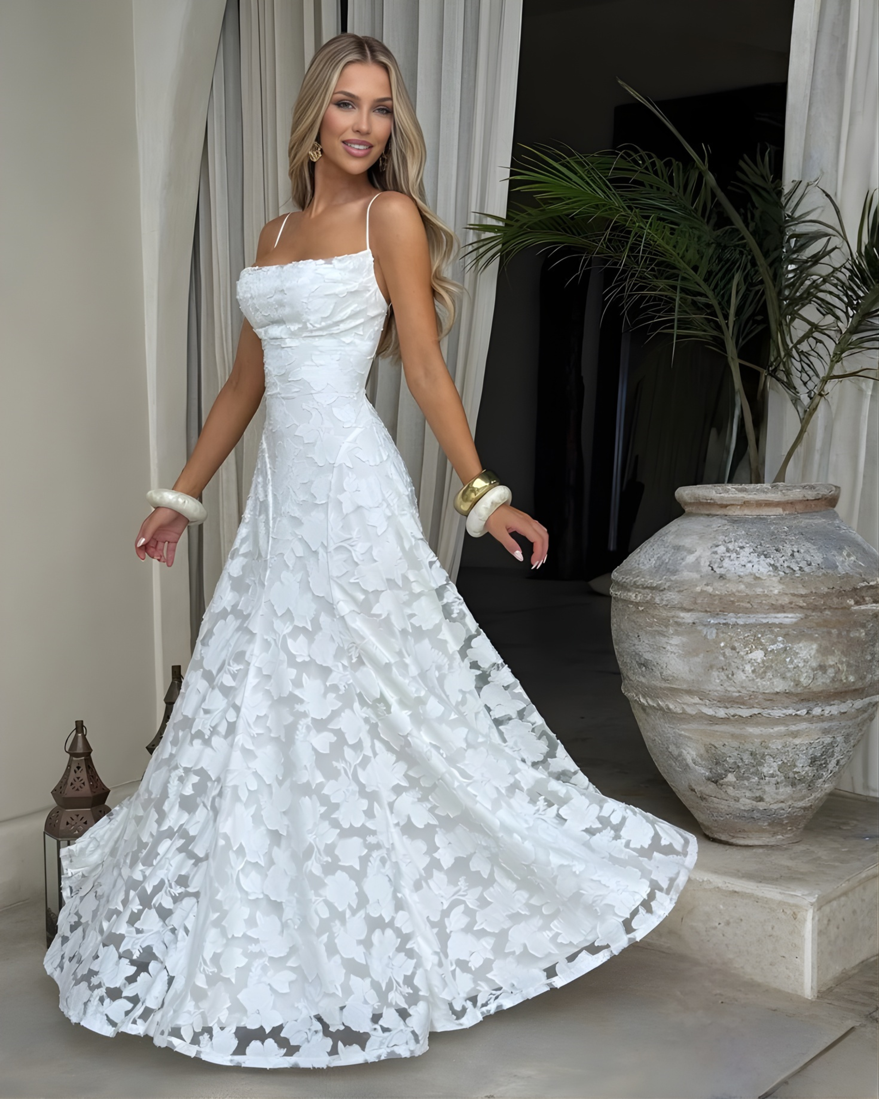 Woman in a white lace dress standing in an elegant indoor setting.