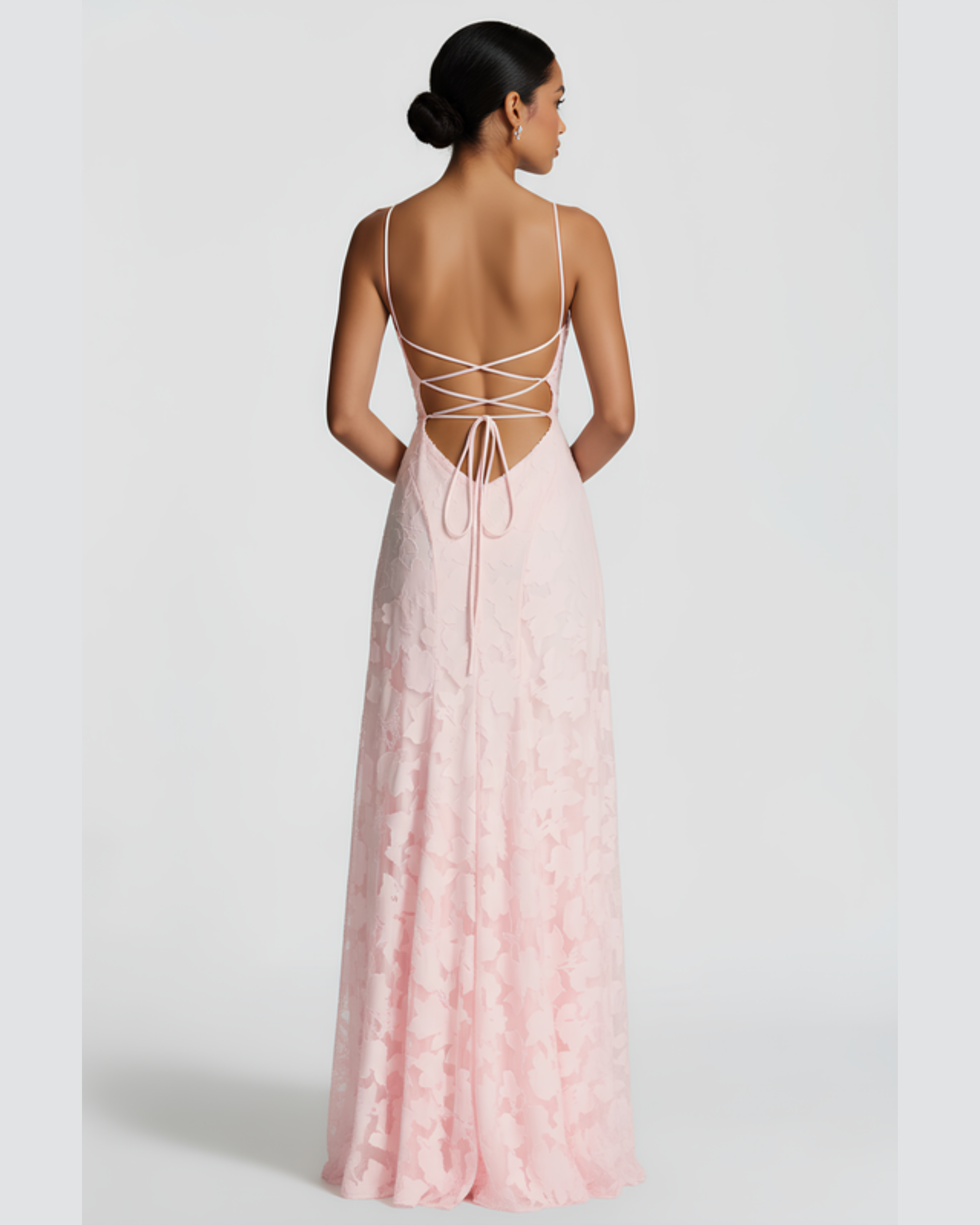 Woman wearing a pink lace dress with an open back on a white background