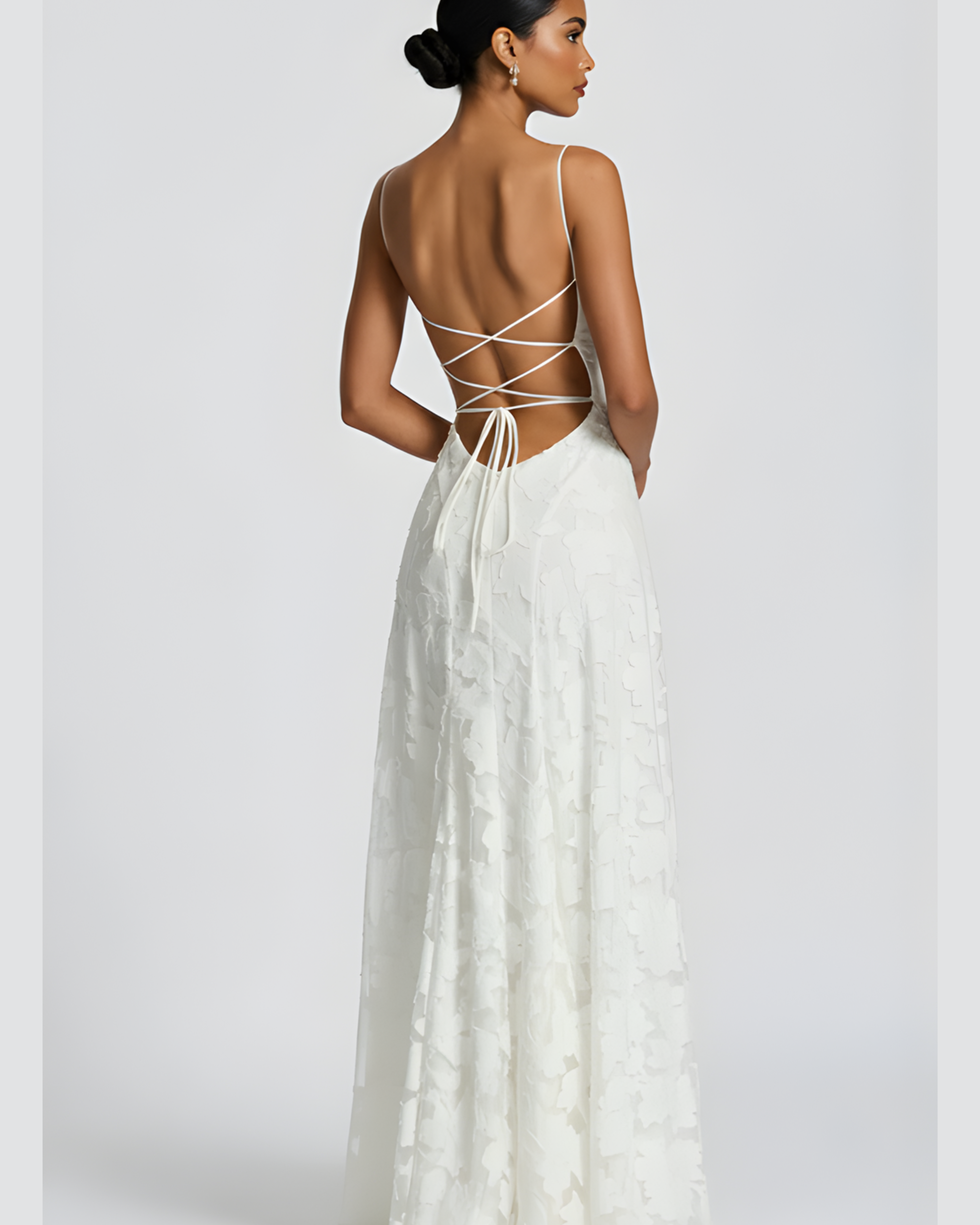 Woman wearing a white dress with a backless design on a plain background